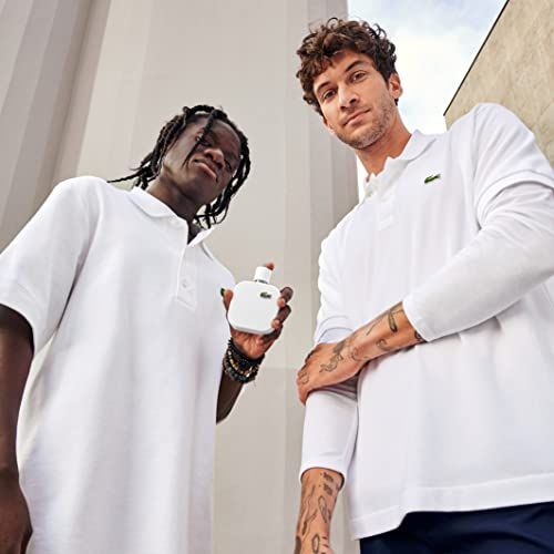 Due uomini in polo bianche. Uno tiene un profumo bianco. Sfondo: edifici.