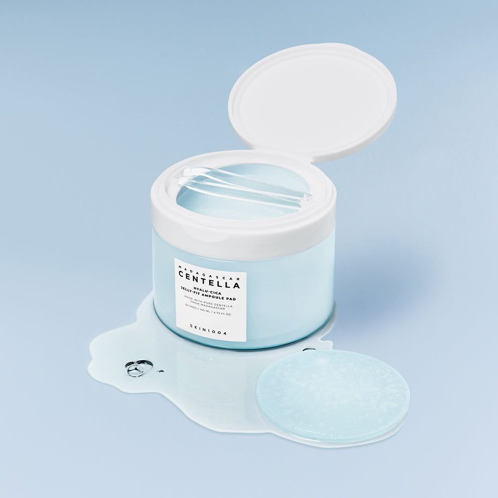 Barattolo aperto con pad. Etichetta SKIN1004. Scritta Hyalu-Cica Jelly Fit Ampoule Pad. Pad e liquido visibili.