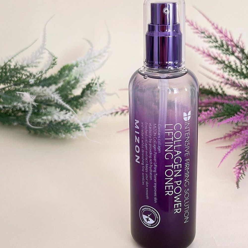 MIZON Collagen Power Lifting Toner. Bottiglia con spruzzatore, etichetta viola, piante verdi e viola sullo sfondo.
