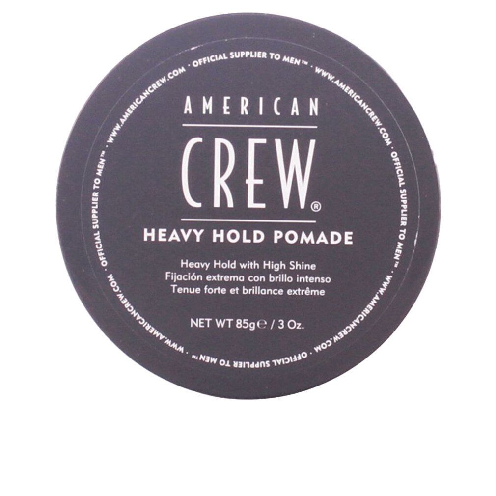 Coperchio nero con scritta: AMERICAN CREW, HEAVY HOLD POMADE. Forma rotonda, nome del prodotto e testo visibili.