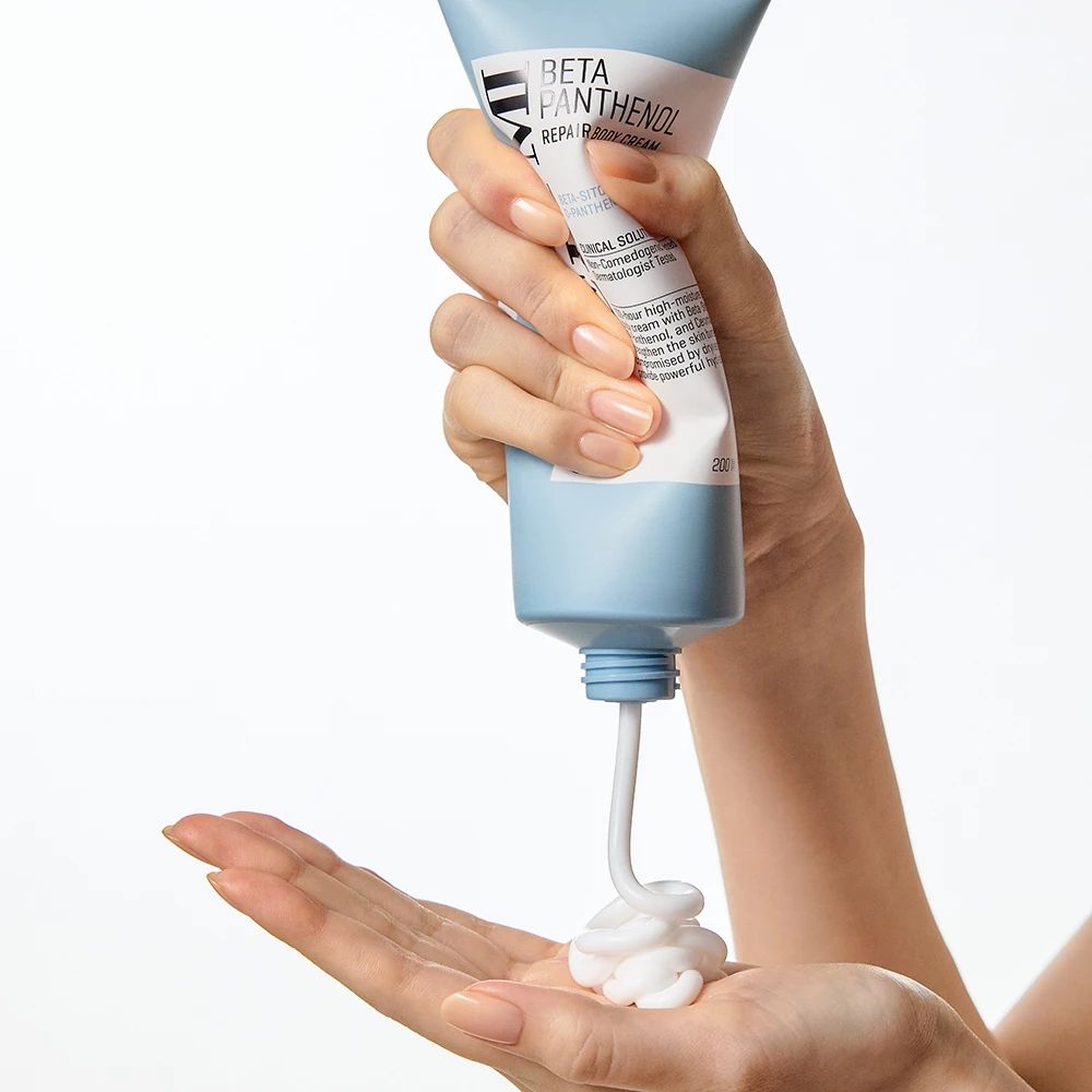 La crema viene spremuta da un tubo blu nella mano. Nome del prodotto e testo sul tubo.