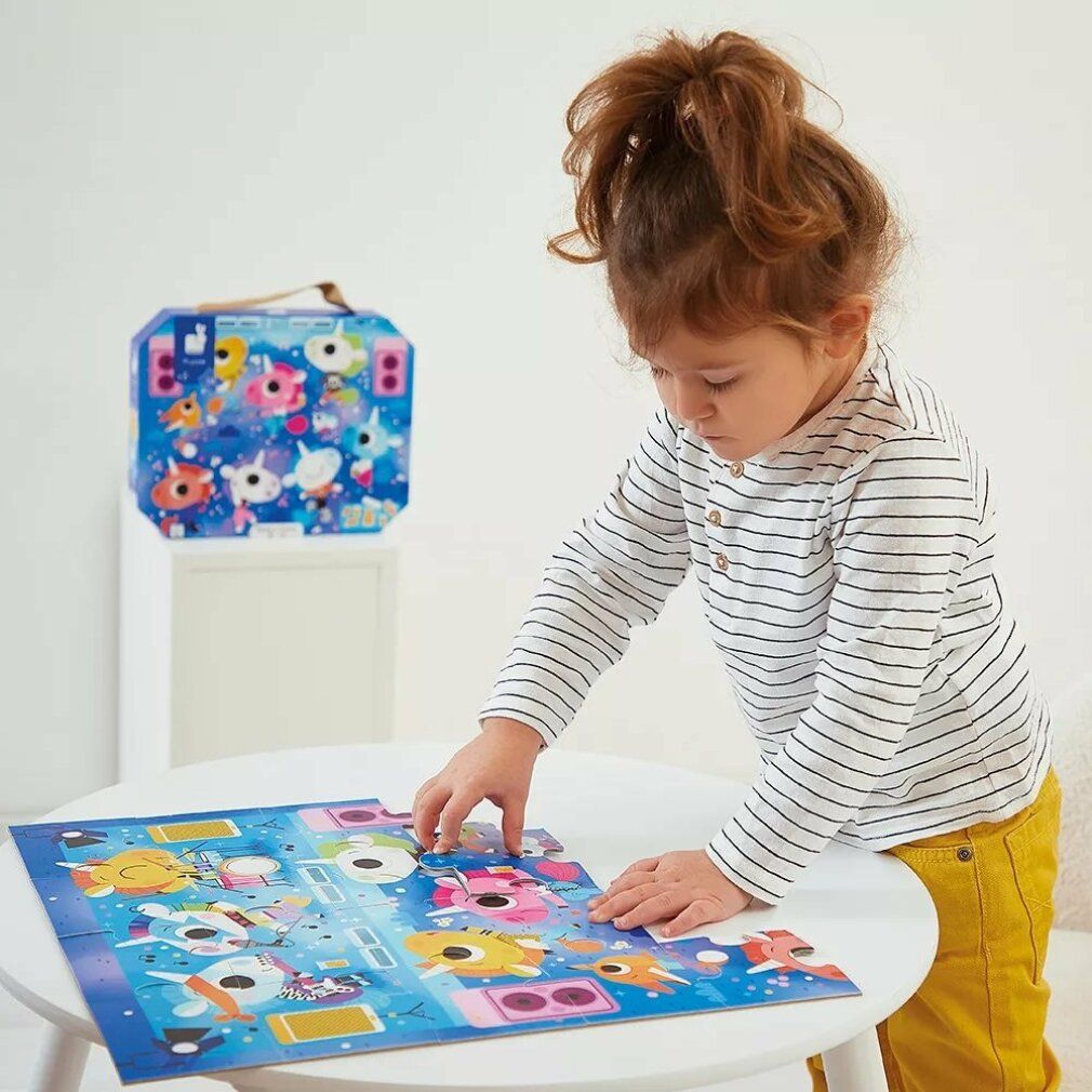 Bambino che gioca con un puzzle. Janod in valigetta. 24 pezzi. Unicorno al concerto. Bambino seduto a un tavolo, che mette pezzi.