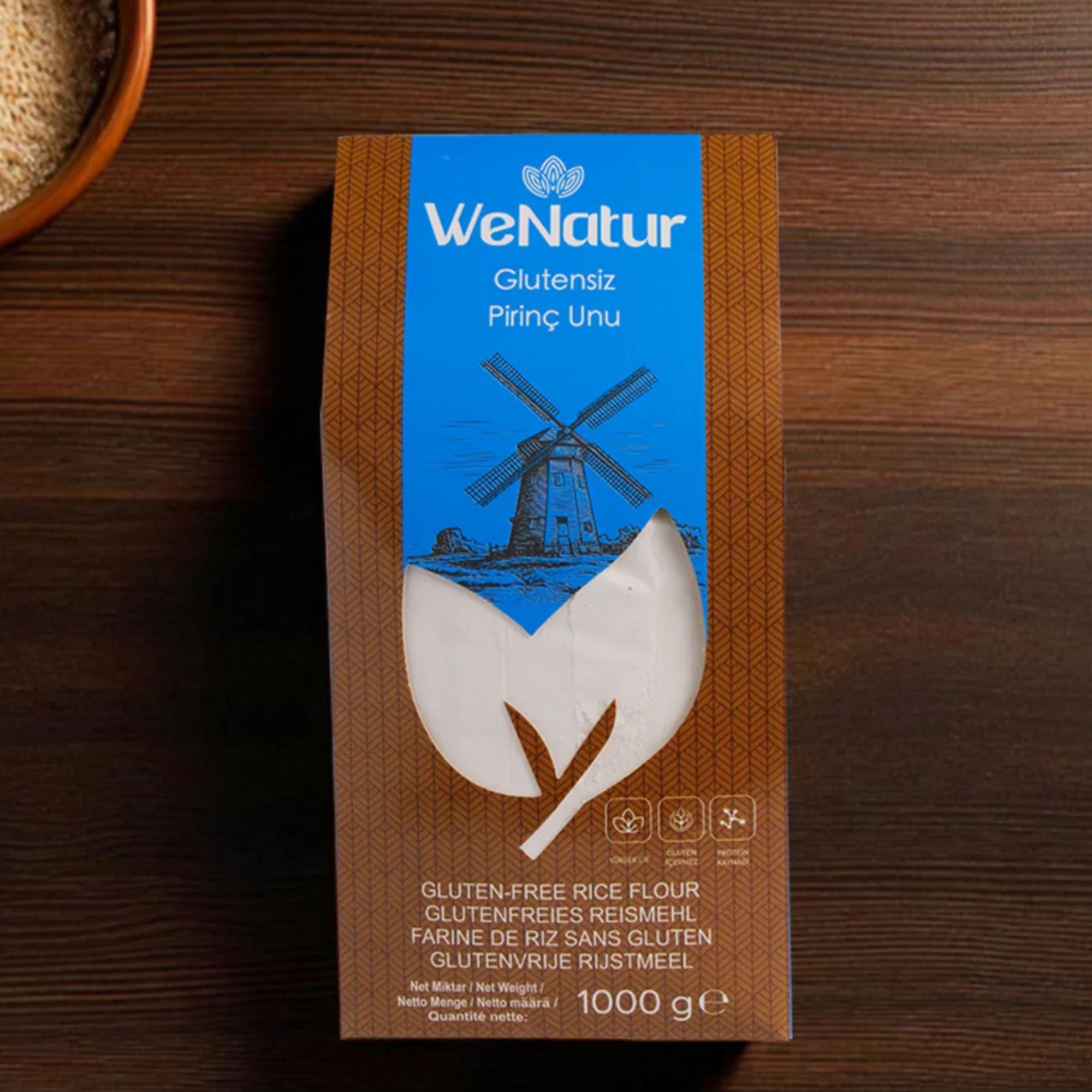 Farina di riso senza glutine WeNatur, confezione da 1000g su un tavolo di legno.