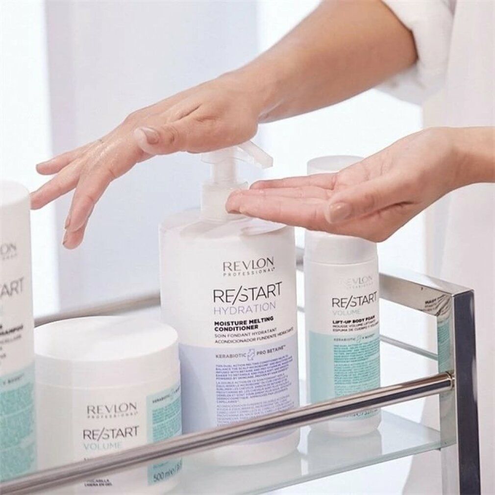 Mani sopra una selezione di prodotti Revlon Re-Start. Visibili: balsamo, shampoo e altri contenitori. Su un carrello in metallo.