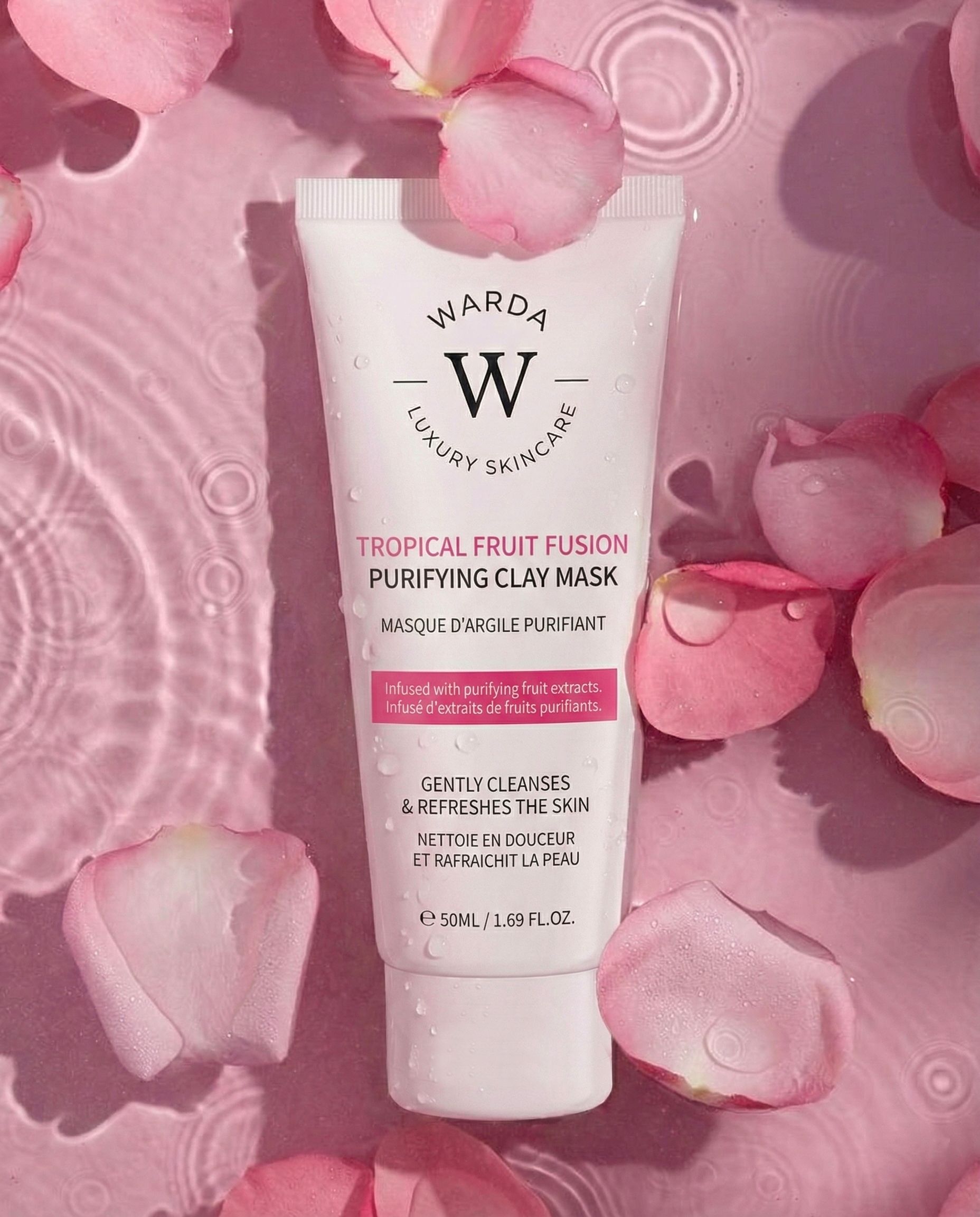 Tubo di maschera all'argilla Warda Luxury Skincare Tropical Fruit Fusion. Testo rosa. Circondato da petali di rosa.