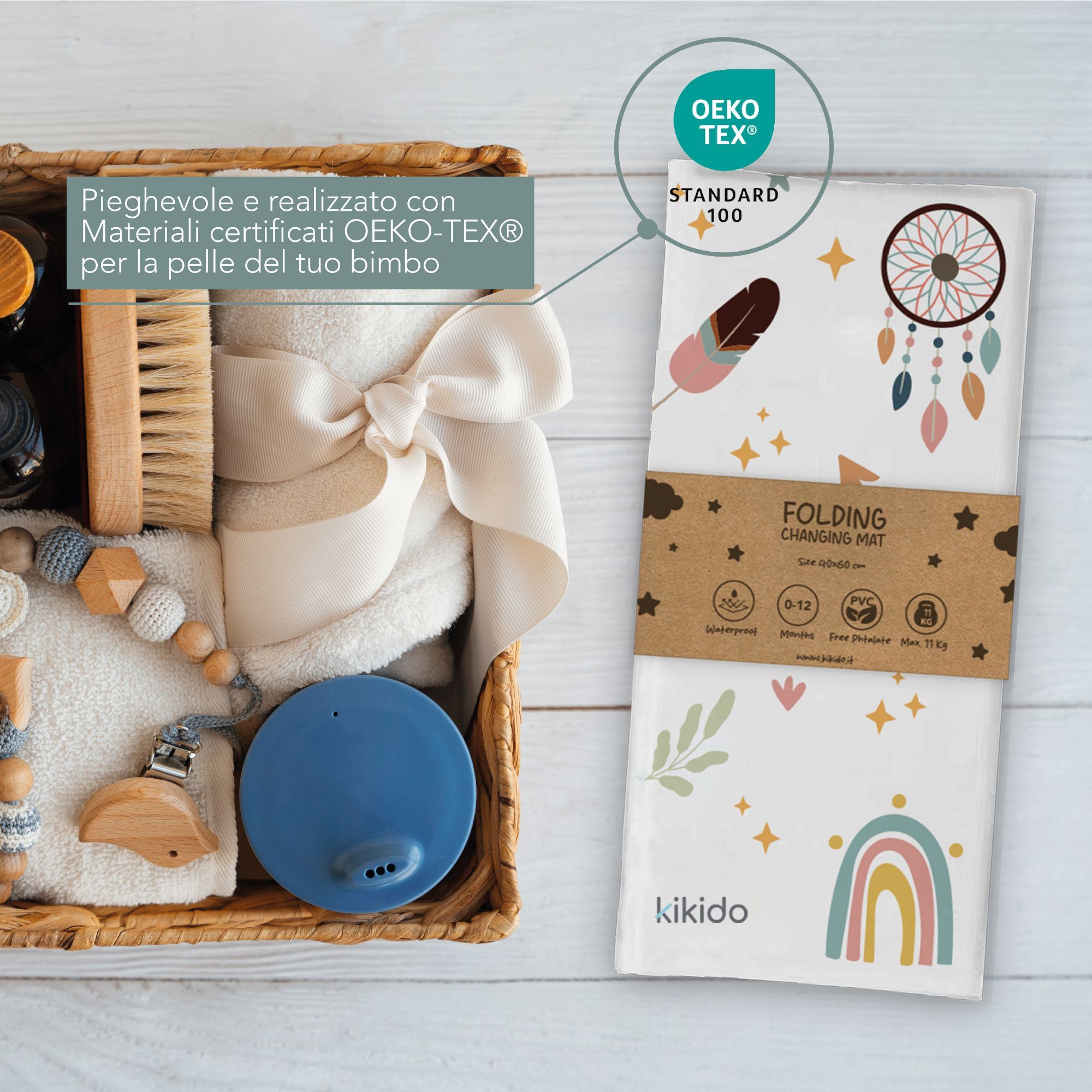 Fasciatoio piegato, certificato Oeko-Tex. Bianco con acchiappasogni, piume e arcobaleno. Logo Kikido. In un cesto.