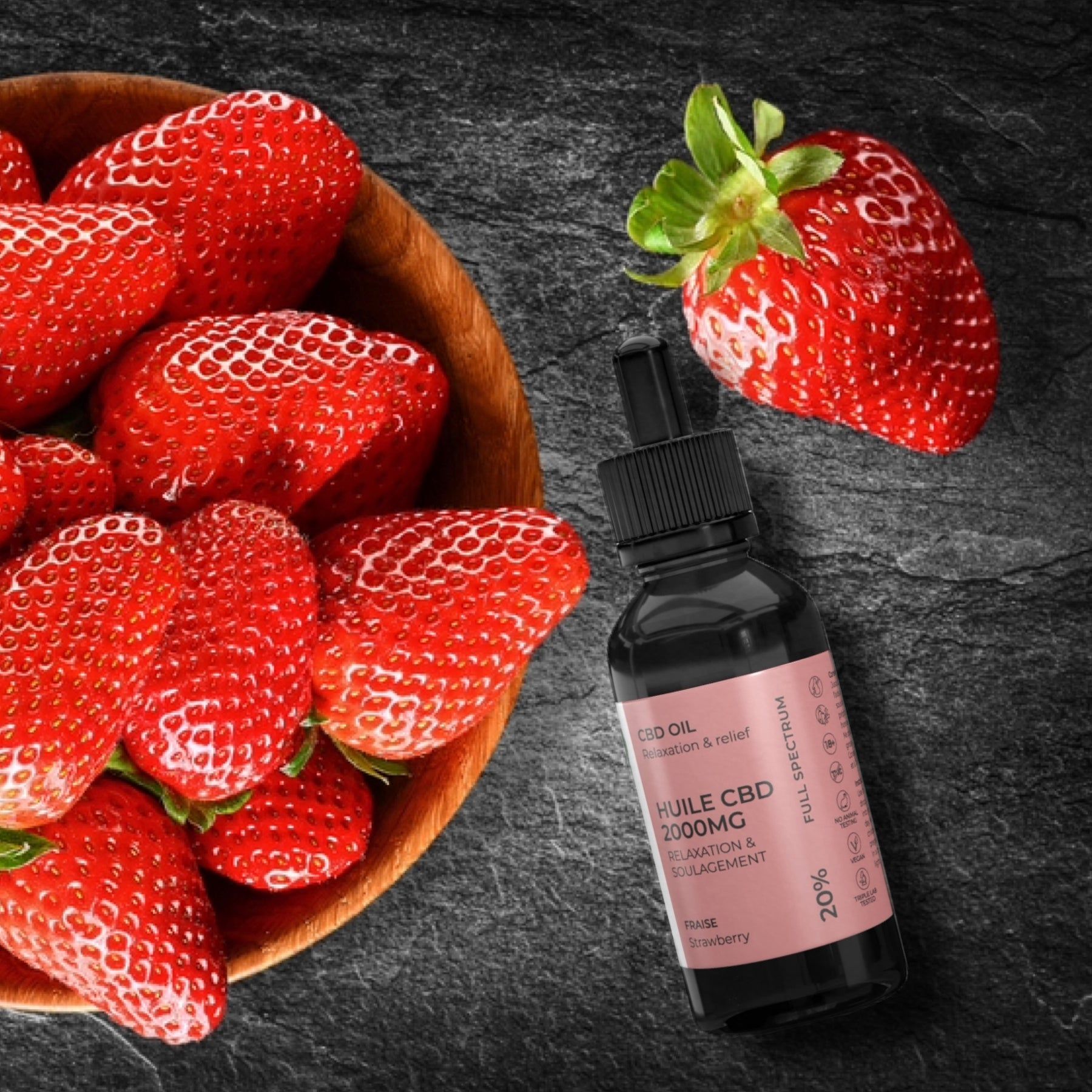 Flacone di vetro con contagocce accanto a fragole in una ciotola di legno. Sfondo nero. Etichetta rosa con informazioni sul prodotto.