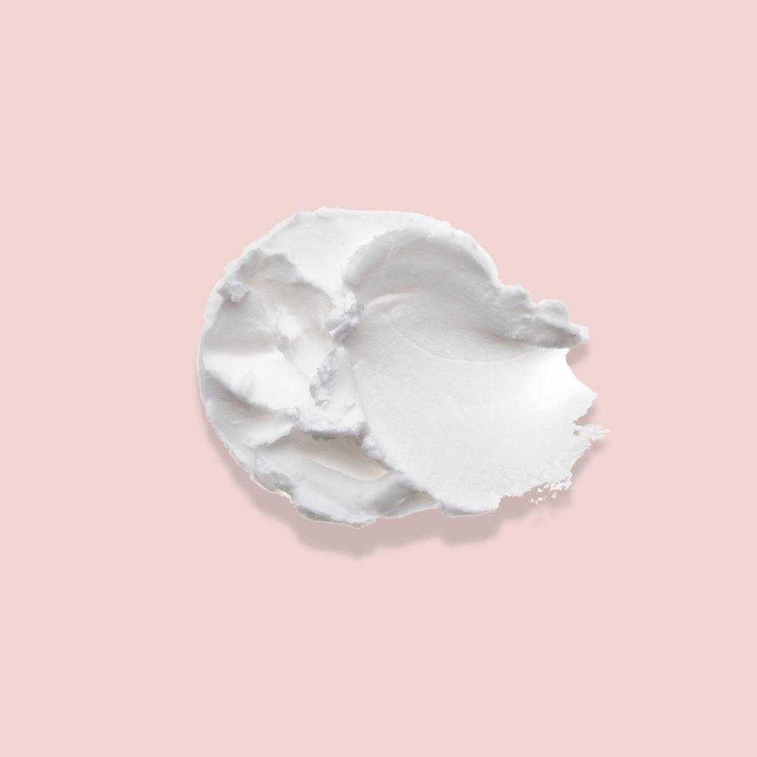 Macchia di crema bianca su sfondo rosa. Consistenza visibile.