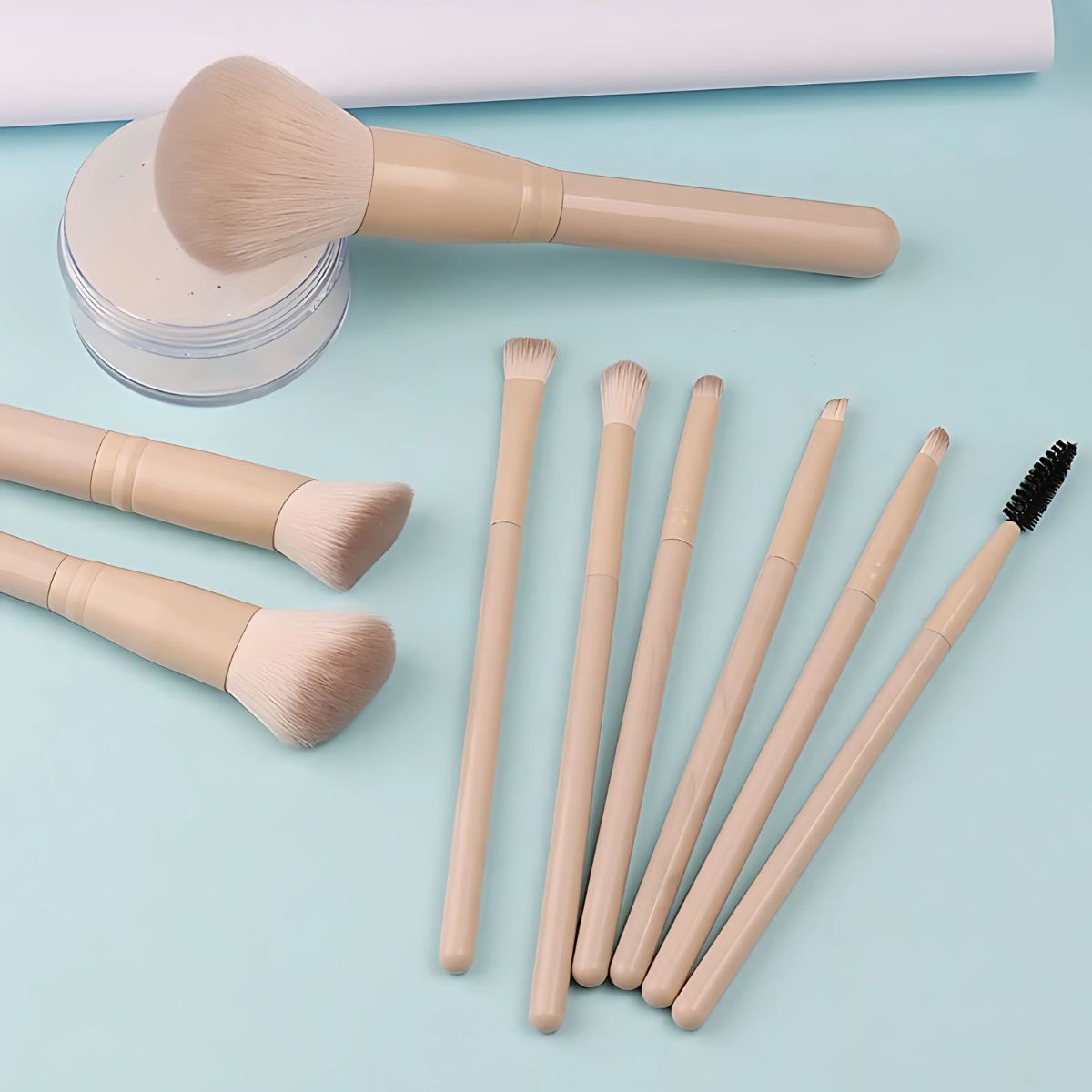 Un set di otto pennelli per il trucco con manici beige chiaro e setole chiare. Un pennello è un grande pennello per cipria, gli altri sono pennelli più piccoli per il trucco degli occhi e uno scovolino per mascara.