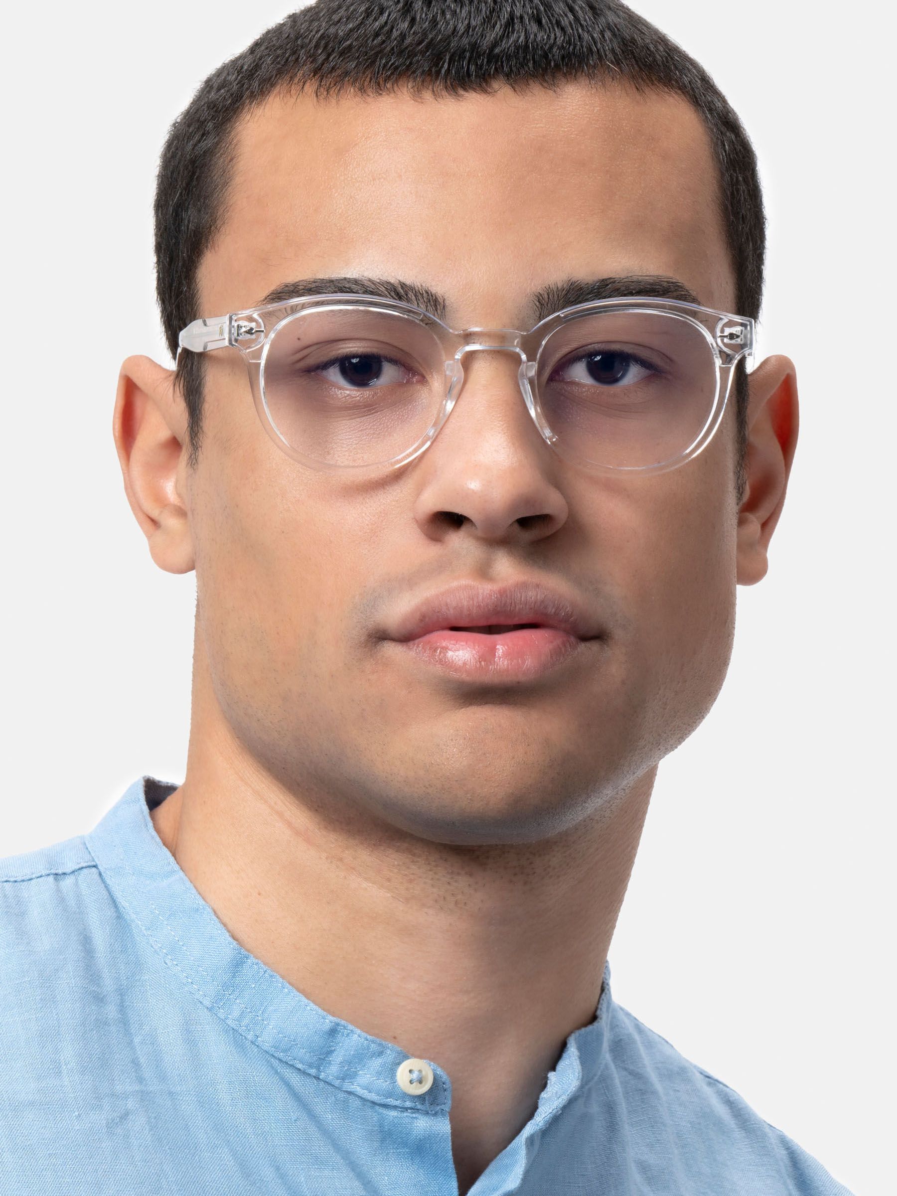 Uomo con camicia blu con occhiali trasparenti con lenti rotonde. "XFT" visibile sull'asta sinistra.