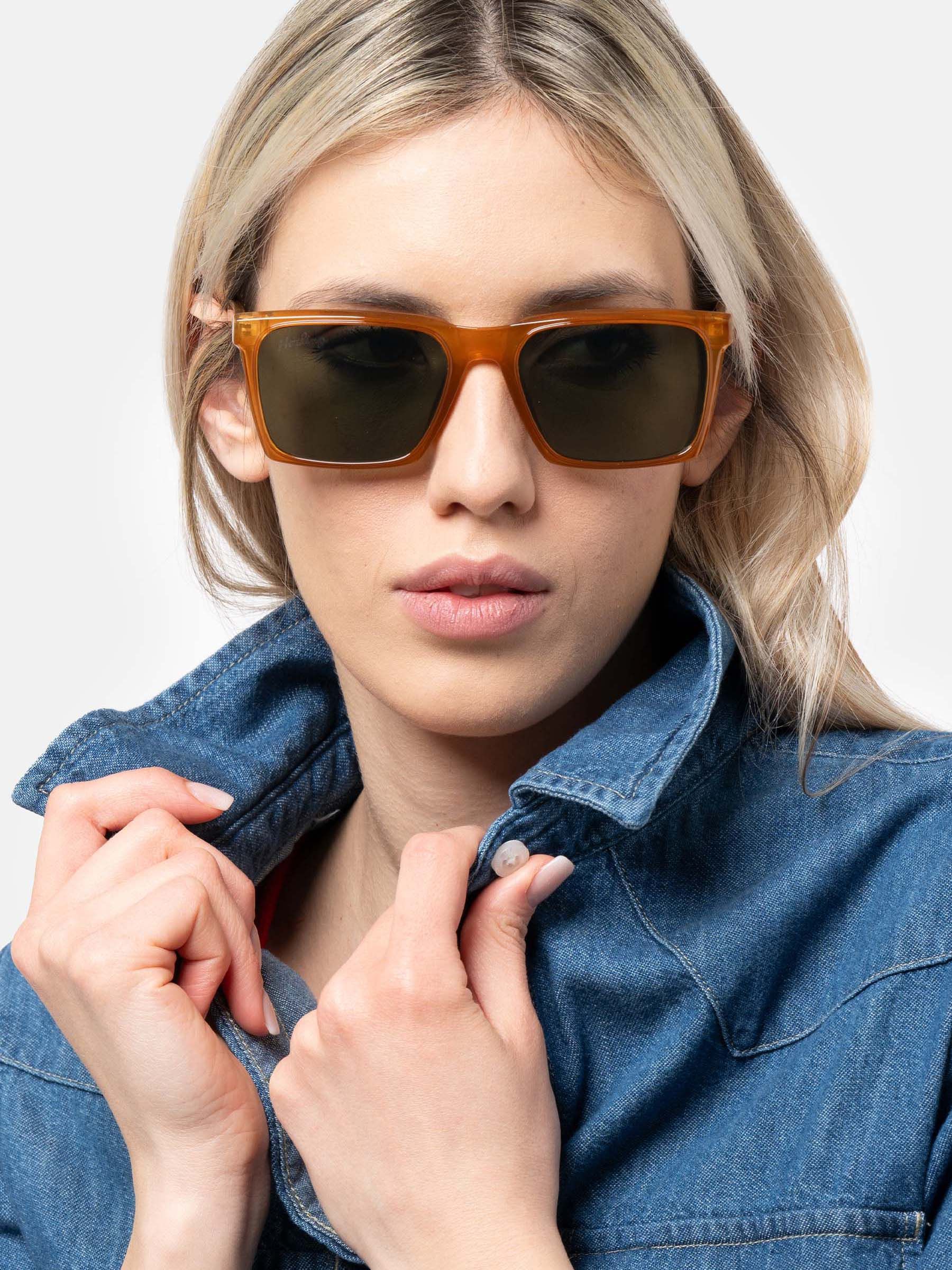 Donna con occhiali da sole marroni e lenti verdi. Giacca di jeans.