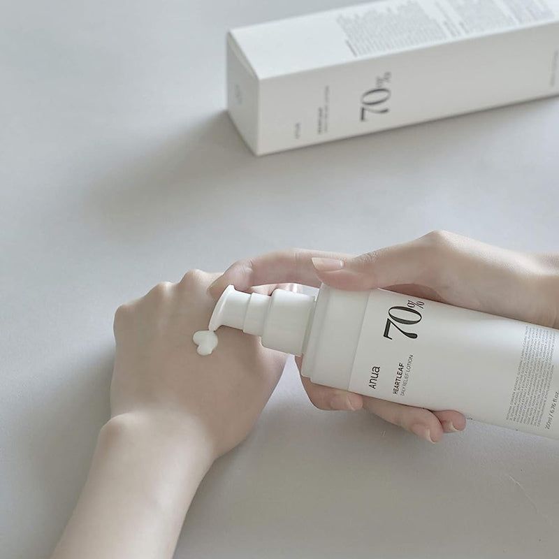 Mani che erogano la lozione da un flacone bianco. Scritta: Anua, Heartleaf 70% Daily Releaf Lotion, 70%.