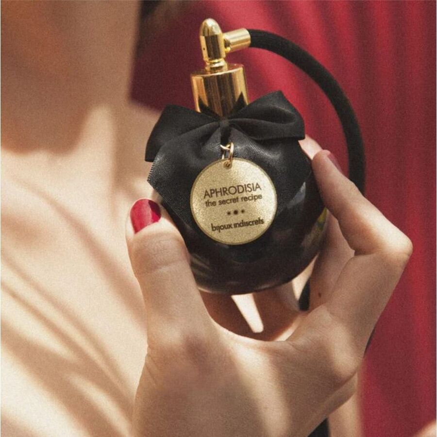 Mano che tiene un nebulizzatore in vetro nero con fiocco nero e targhetta dorata.