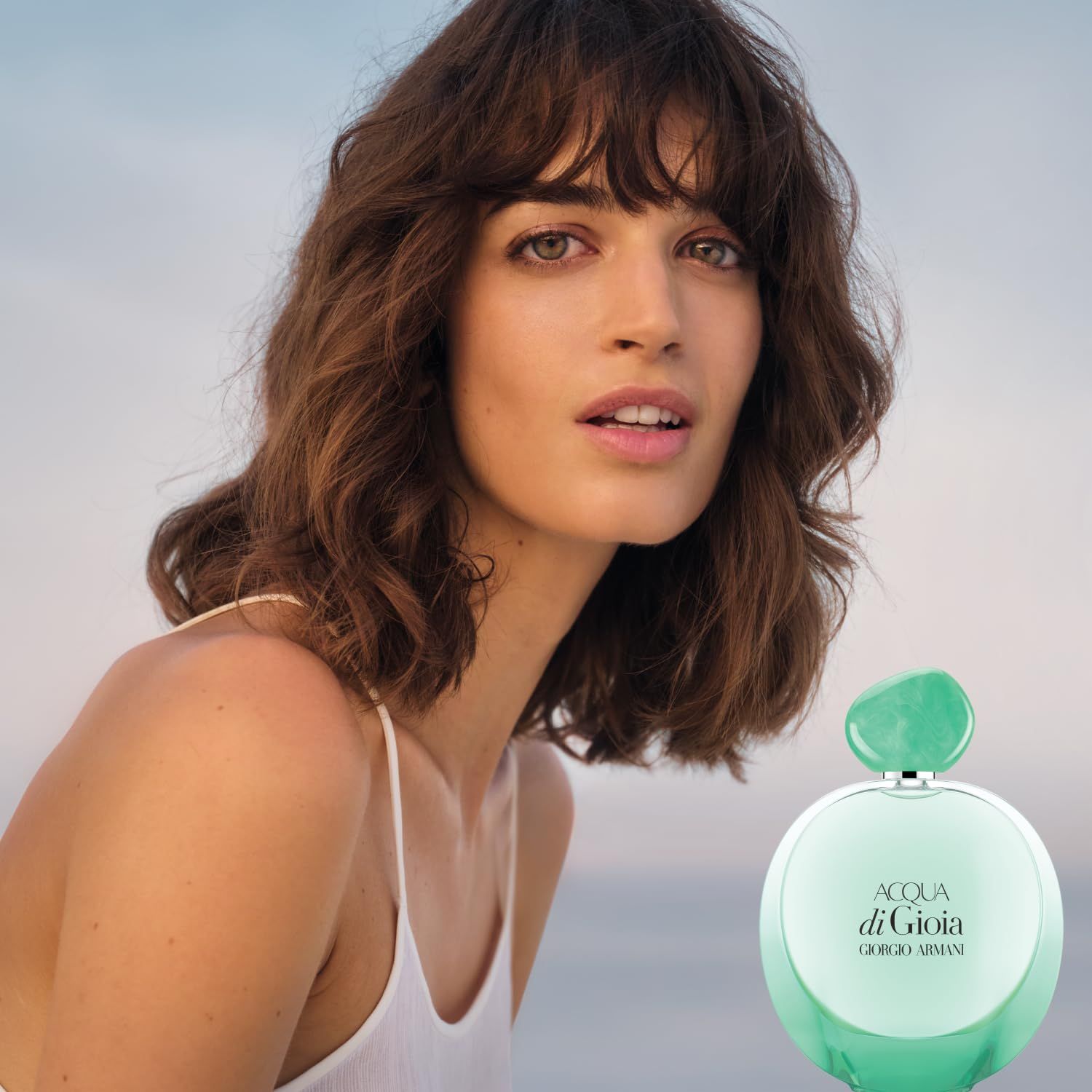 Donna con flacone Acqua di Gioia. Flacone con tappo verde. Testo: Acqua di Gioia, Giorgio Armani.