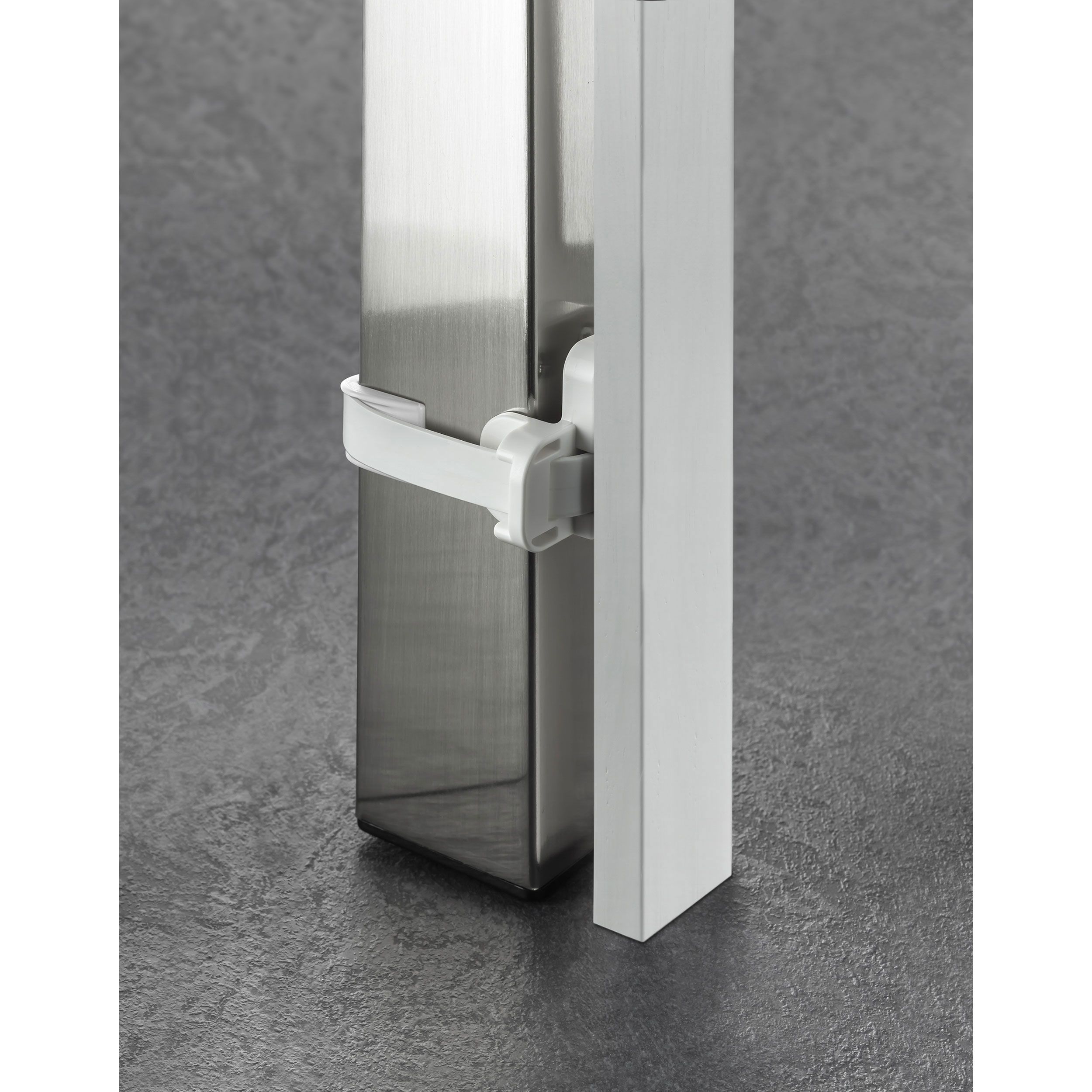 Elemento bianco con supporto bianco fissato a un cilindro metallico. Pavimento grigio. Il supporto è bianco.