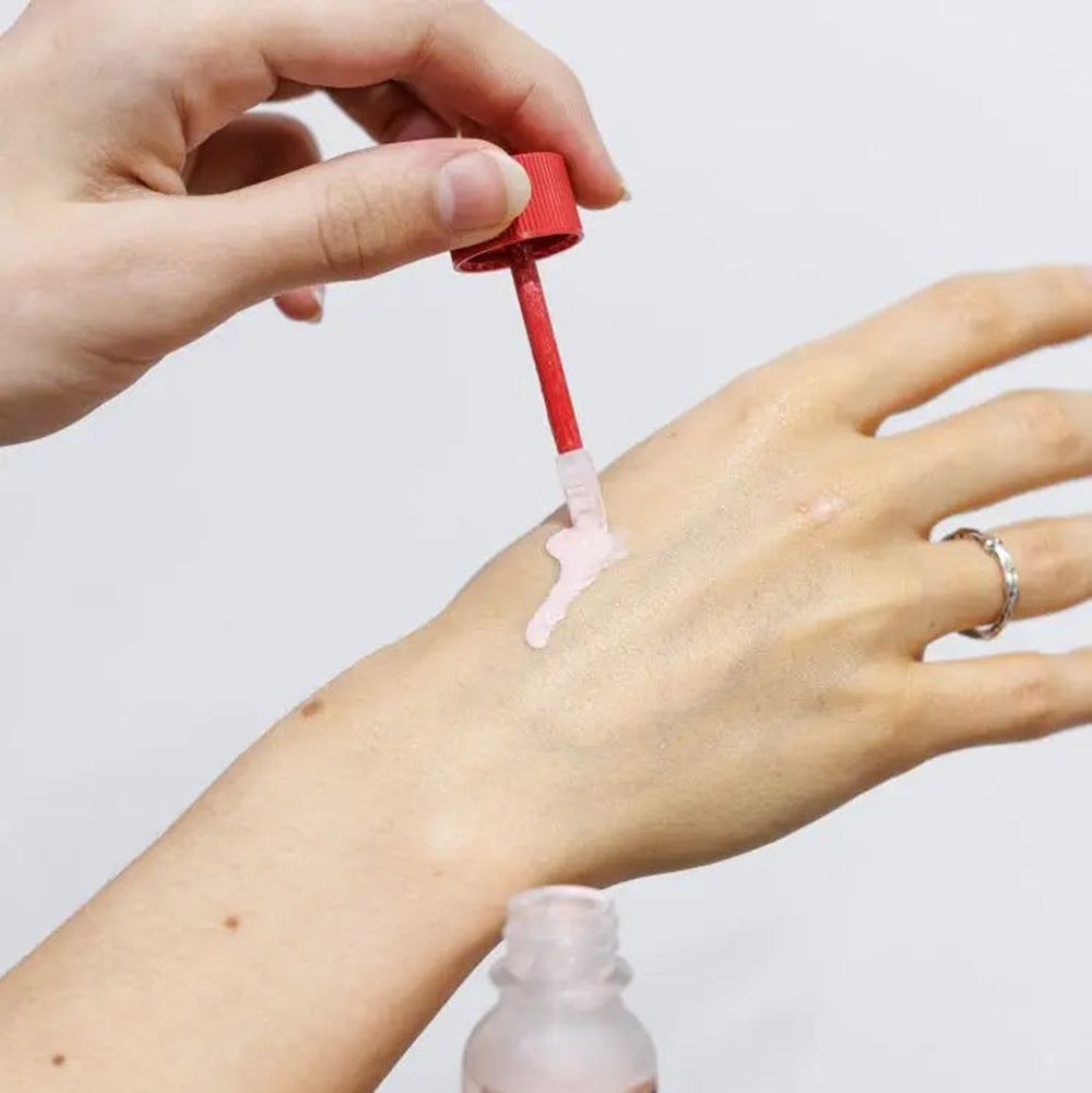 Applicatore con polvere rosa applicata su una mano.