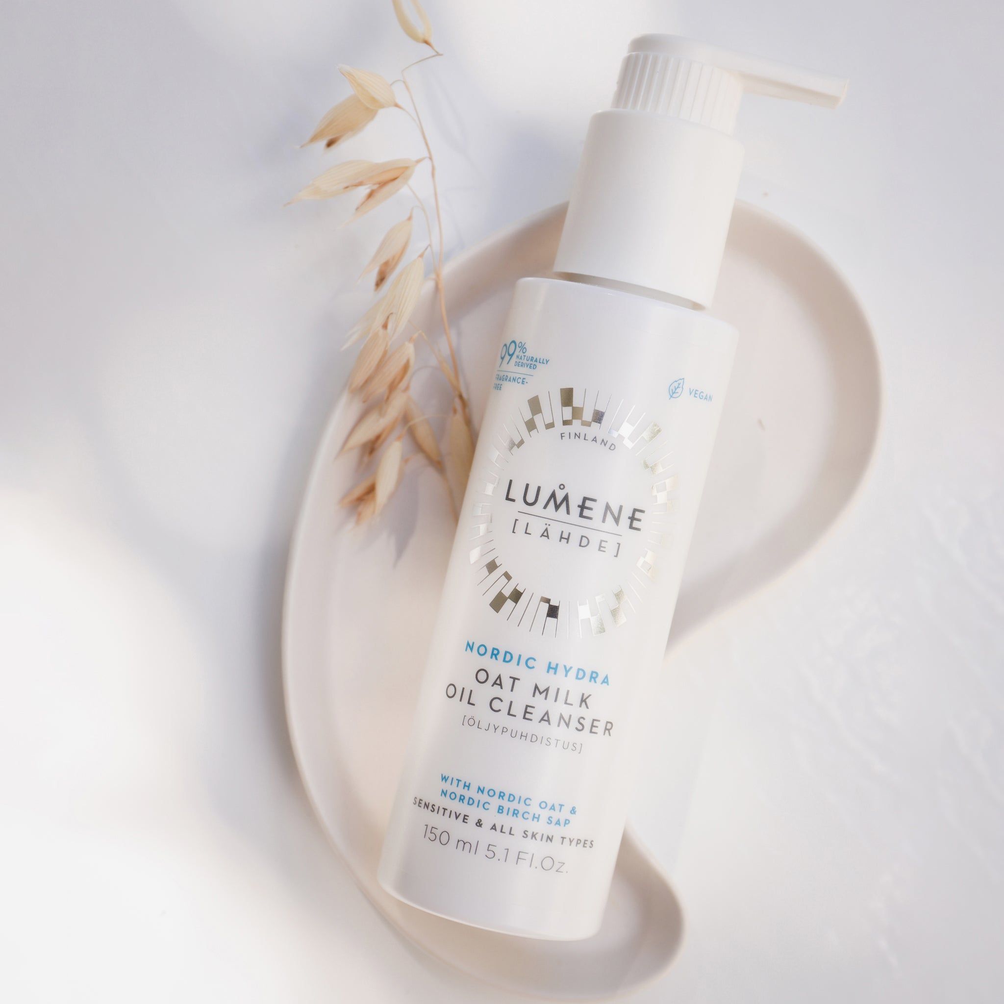 Flacone bianco con dosatore su un vassoio. Scritta: Lumene Nordic Hydra Oat Milk Oil Cleanser. Con latte d'avena. 99% naturale.