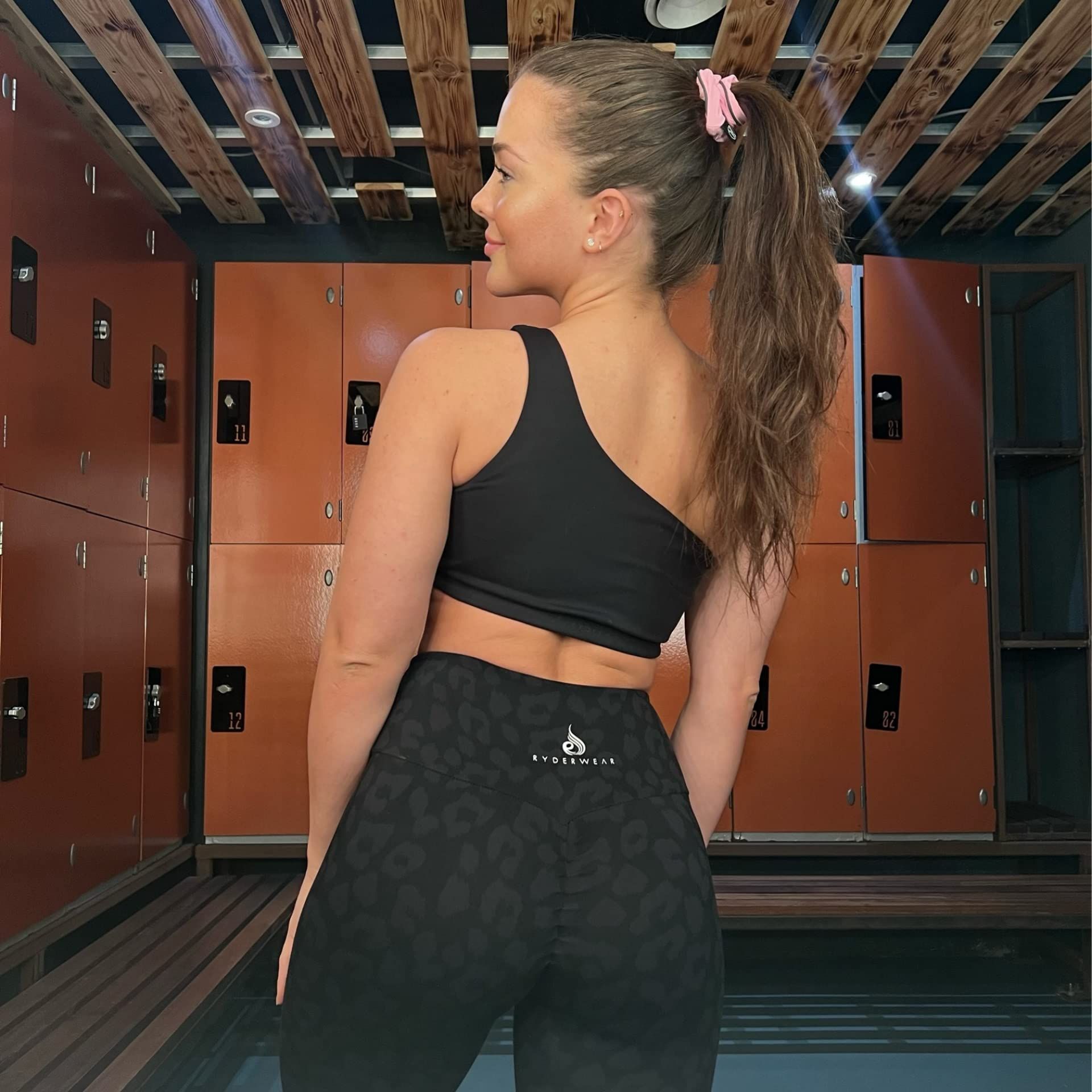 Donna con coda di cavallo, indossa abbigliamento sportivo. Scrunchie rosa nei capelli.