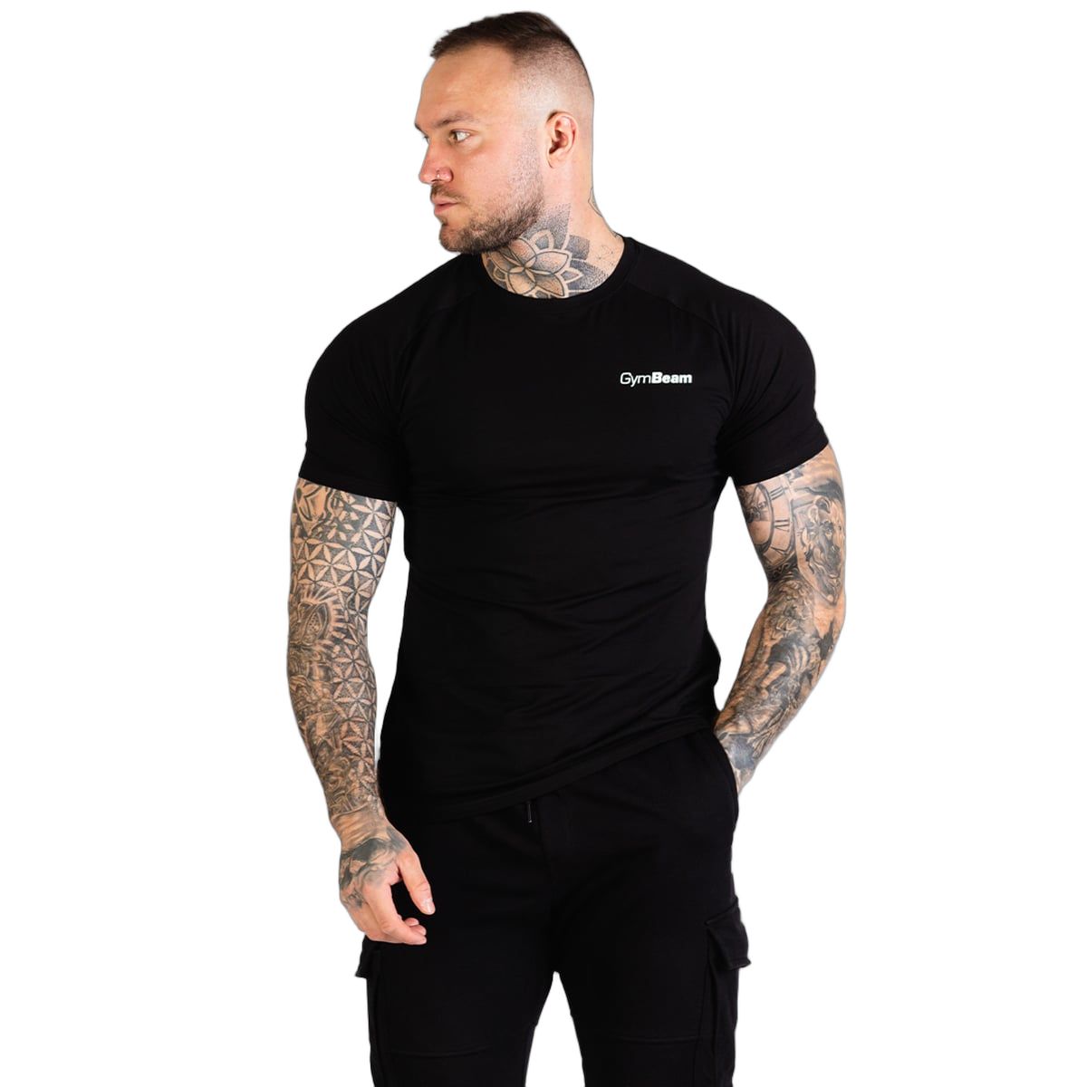 Uomo con t-shirt nera GymBeam e pantaloni cargo, in piedi di lato, guarda a sinistra.