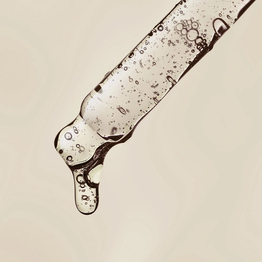 Primo piano di una pipetta con siero. Siero con bolle. Liquido che gocciola.