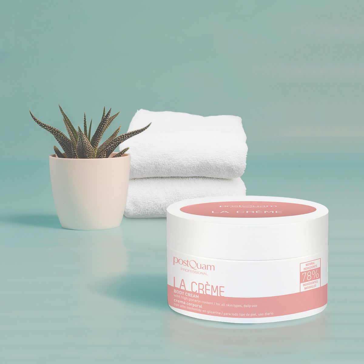 Vaso bianco con coperchio rosa, scritta La Crème e PostQuam. Accanto, vaso con pianta e asciugamani bianchi.