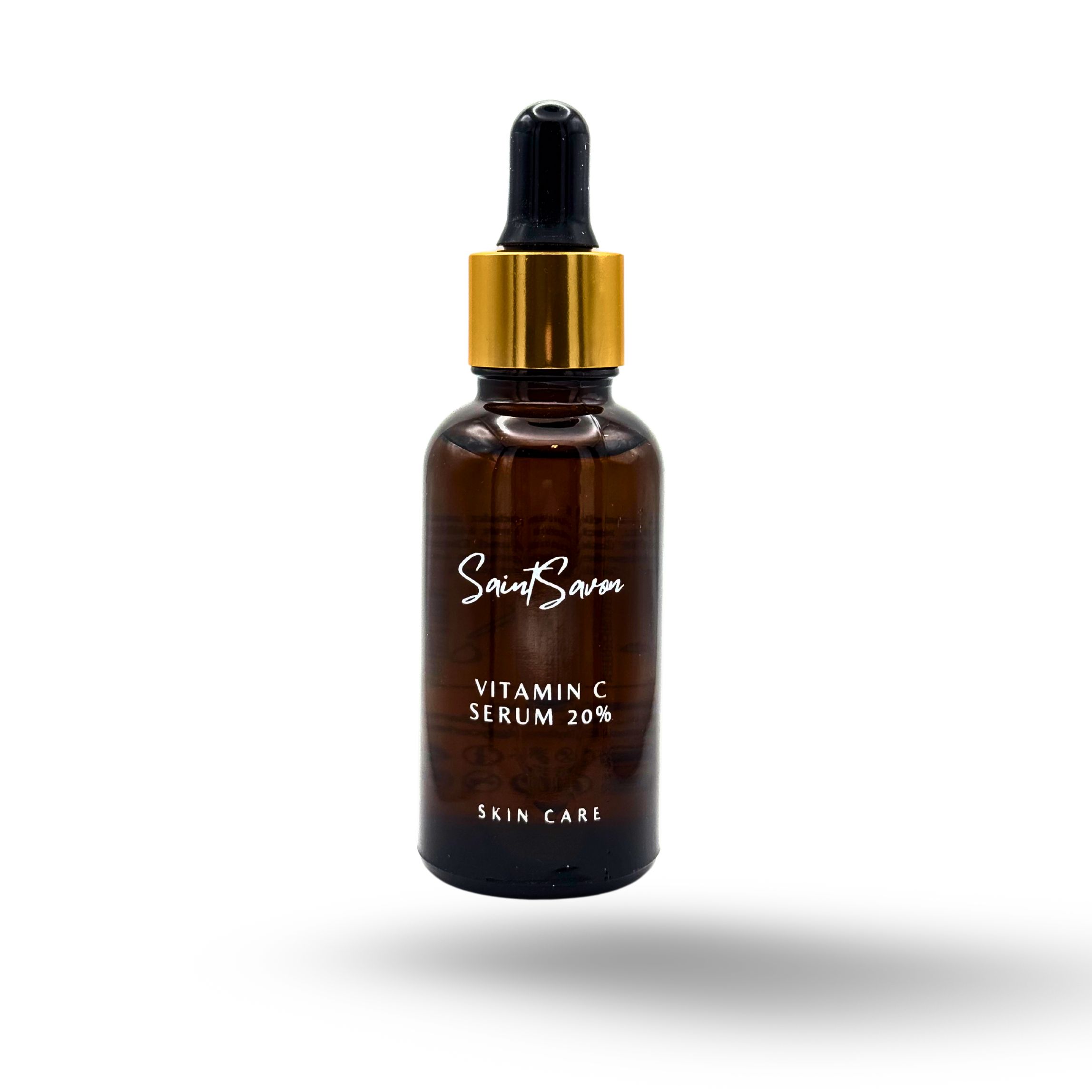 Flacone di vetro marrone con tappo dorato e pipetta. L'etichetta riporta "Saint Savon", "Vitamin C Serum 20%" e "Skin Care".