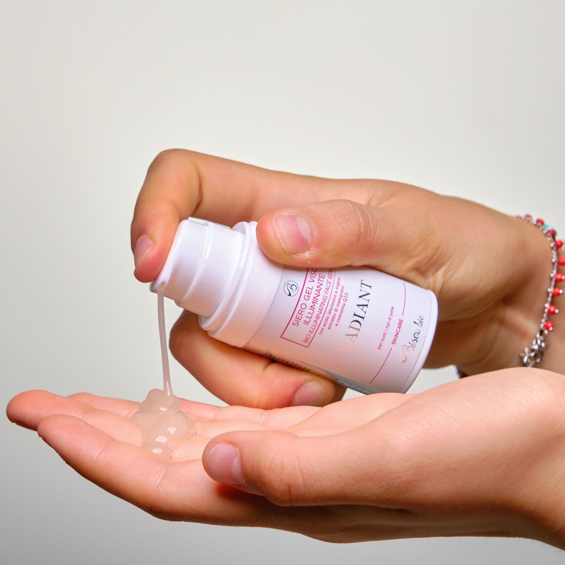 Flacone bianco, prodotto versato nella mano. Testo: Siero Gel Viso Illuminante Radiant.