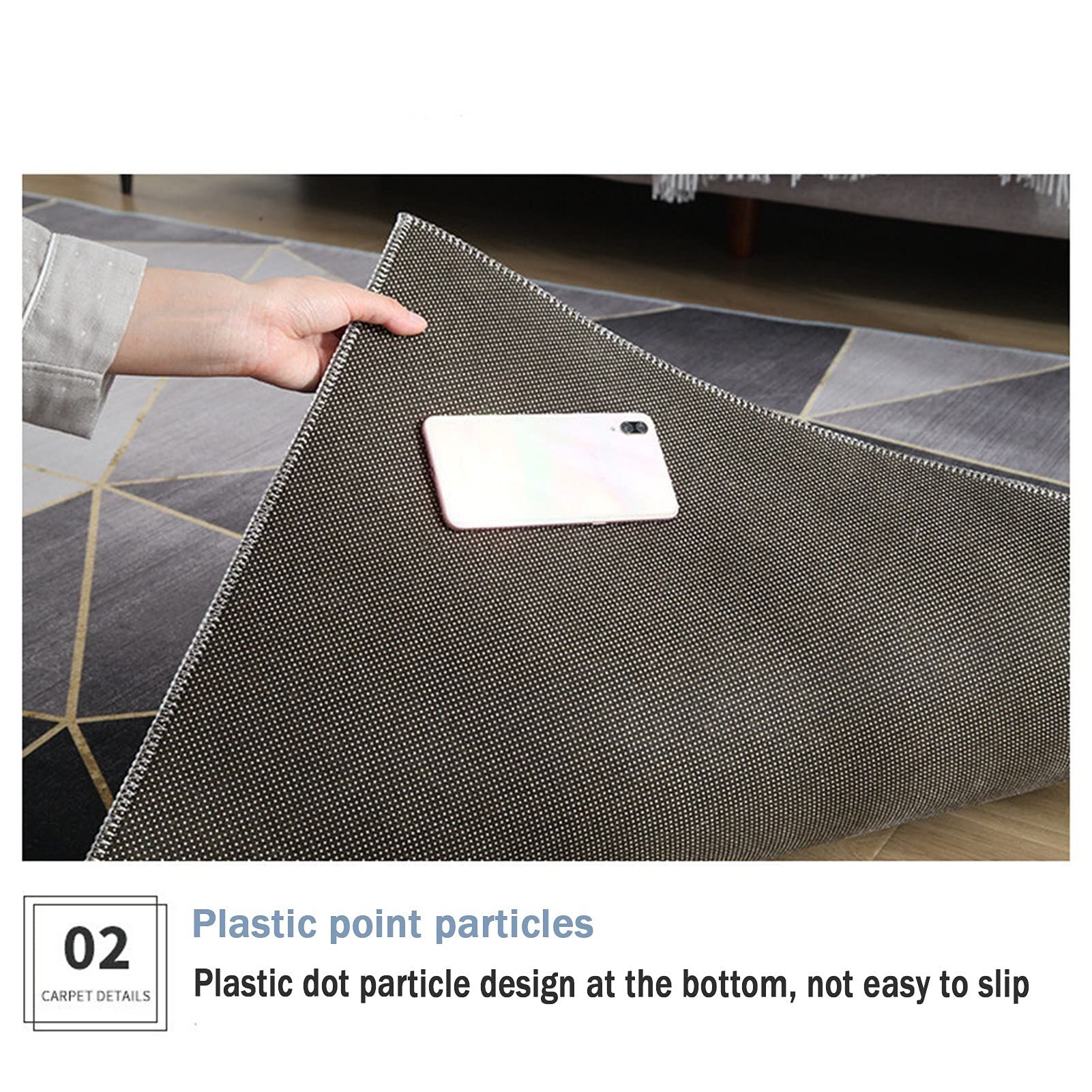 Tappeto grigio con motivo geometrico. Una mano tiene uno smartphone sul tappeto, con punti neri.