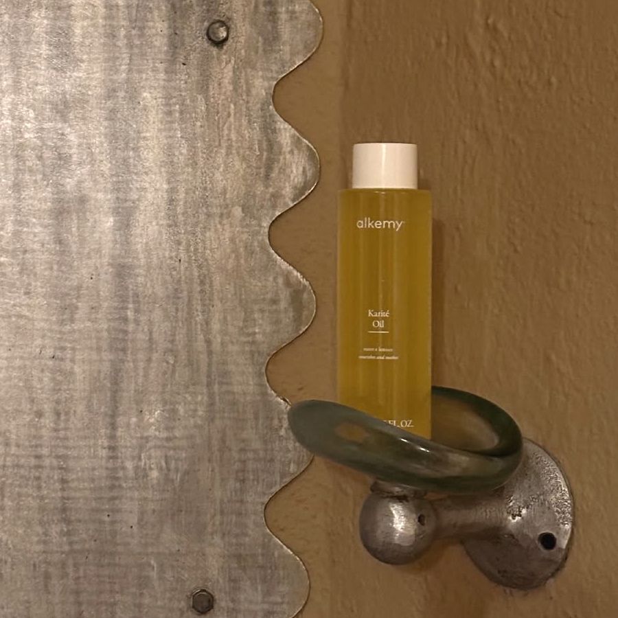 Flacone di olio Alkemy Karité in un portaoggetti decorativo.