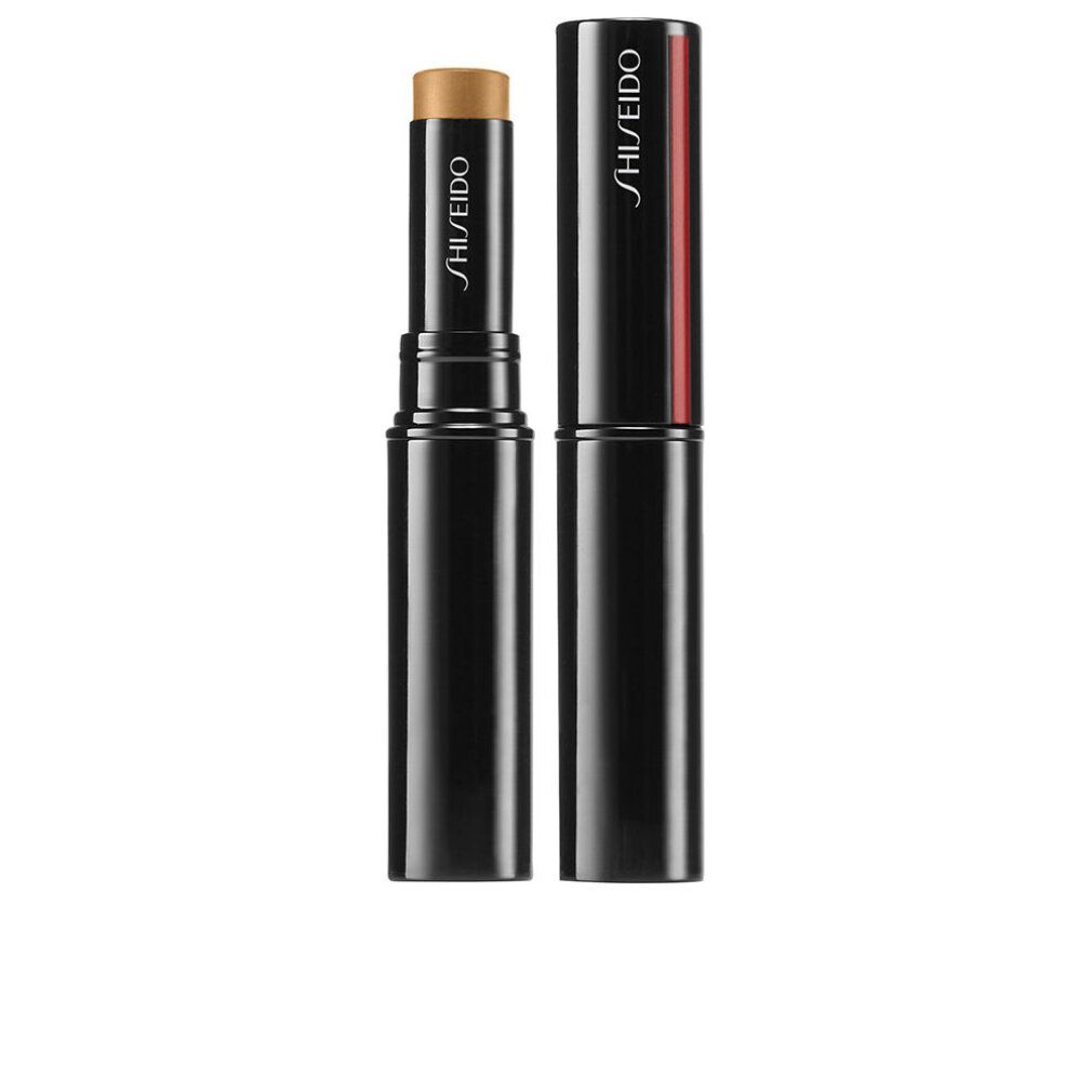 Stick correttore blu scuro con striscia rossa. Tappo accanto. Nome del prodotto e marchio: SHISEIDO. Stick color crema.