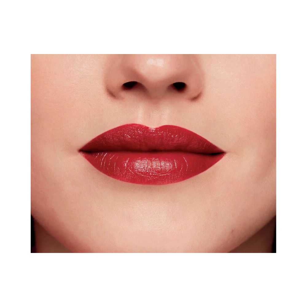 Primo piano di labbra con rossetto rosso. Le labbra sono lucide e piene. Sfondo bianco.