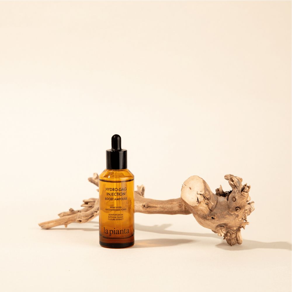 Flacone di vetro marrone con contagocce nero e legno. Scritta: HYDRO-GAG INJECTION BOOST AMPOULE. Marchio: la pianta.