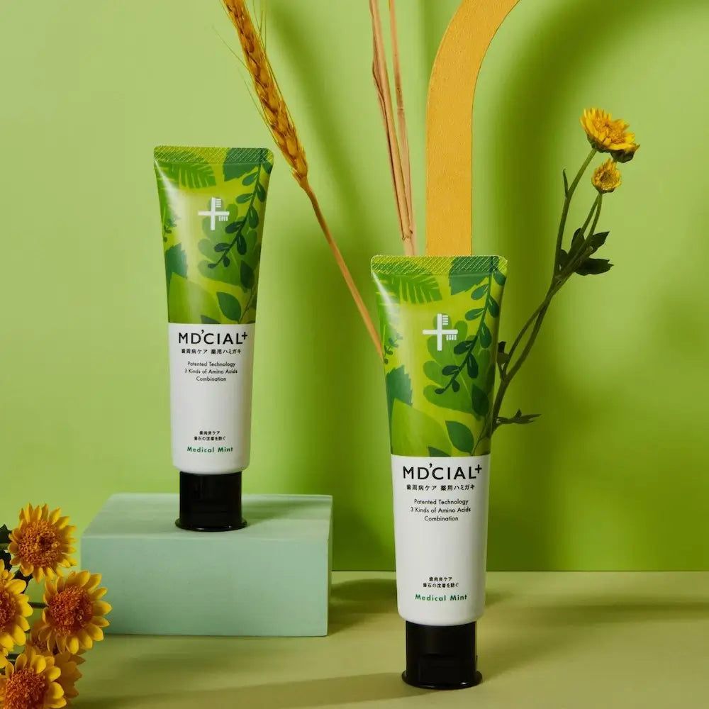 Due tubi di dentifricio MD'CIAL+. Design verde, scritta Medical Mint. Tappo nero. Decorazione floreale.