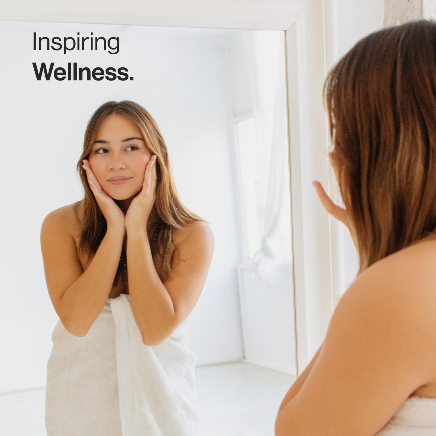 Donna che si guarda allo specchio. È avvolta in un asciugamano. Testo: Inspiring Wellness.