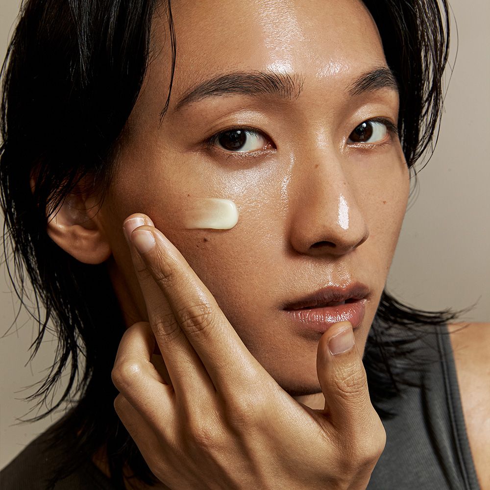Una persona applica la crema viso K-Secret Seoul 1988 sulla guancia.
