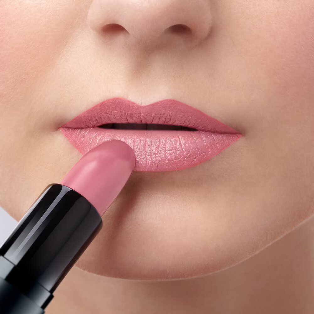 Persona che applica rossetto rosa sulle labbra. Rossetto nero.