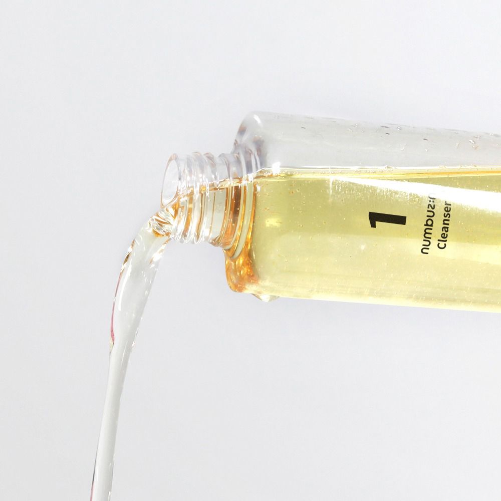 Olio detergente trasparente versato da un flacone. Scritta: 1, Cleanser.