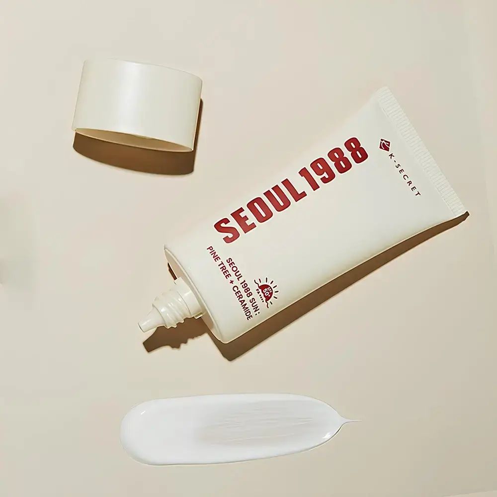 Tubo bianco con scritta rossa SEUL 1988 e logo K-SECRET. Accanto, una striscia di crema. Tappo aperto.