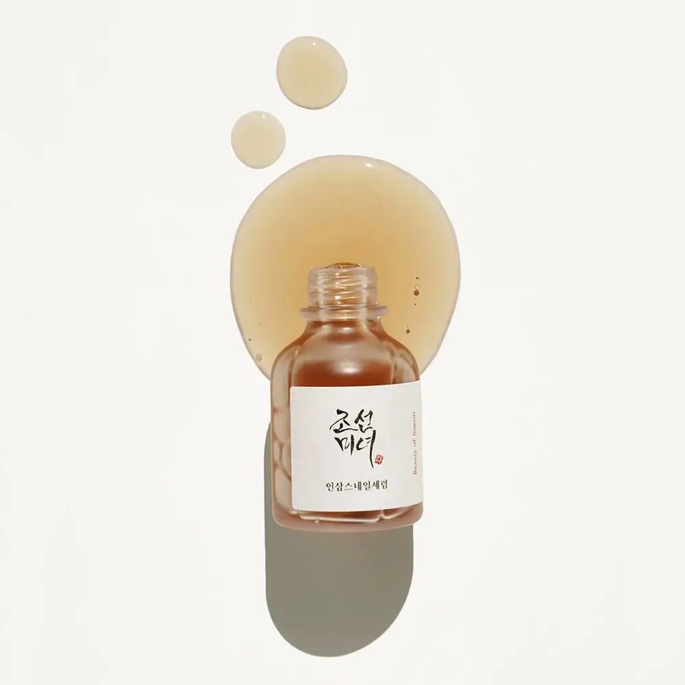 Flacone trasparente con siero e gocce. Etichetta con scritta coreana. Su sfondo chiaro.