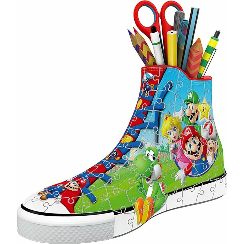 Puzzle 3D assemblato a forma di scarpa con motivi di Super Mario. Contiene penne, matite e forbici. Personaggi di Mario, Luigi, Peach e Yoshi.
