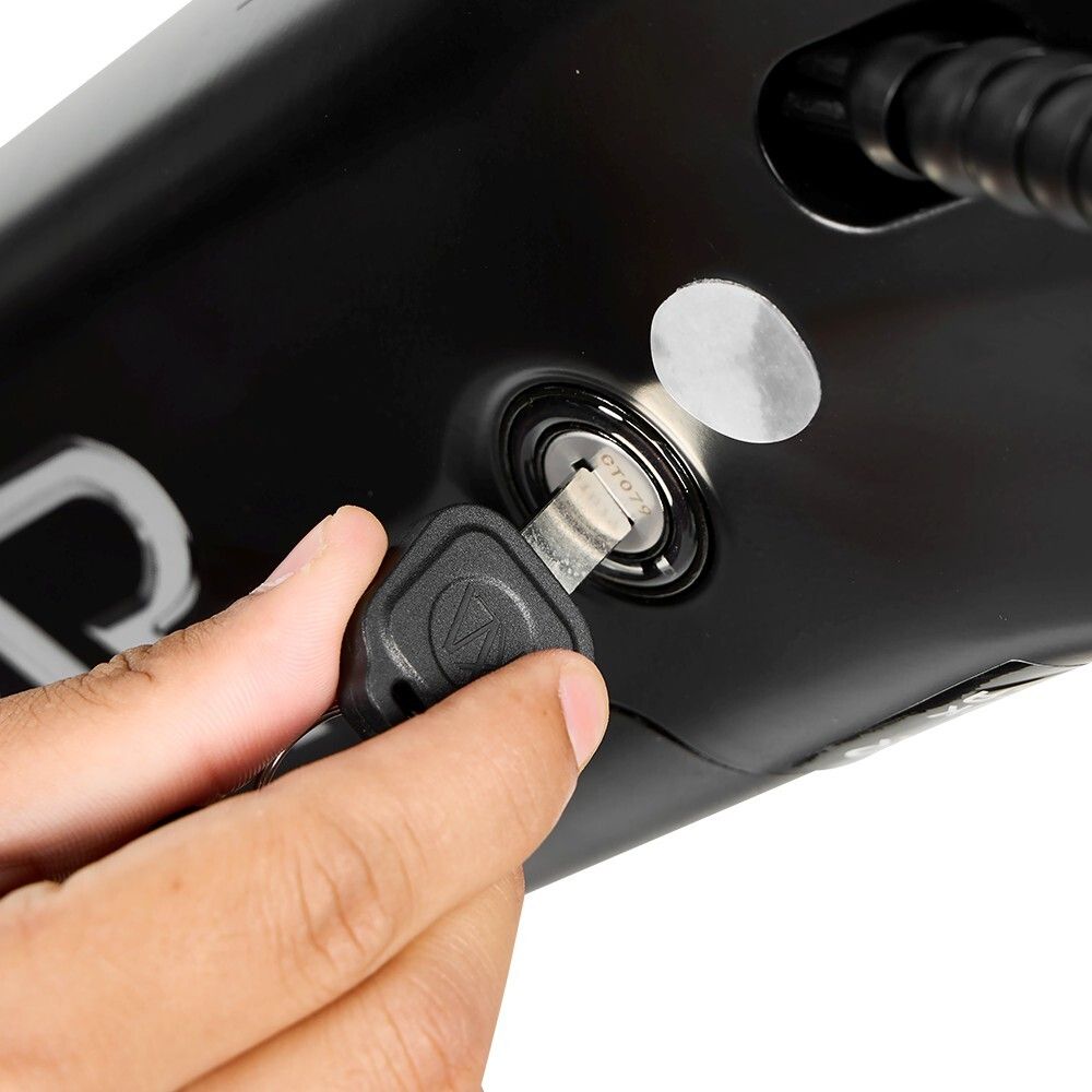 Primo piano: chiave inserita nell'accensione di una e-bike nera. Visibili: chiave, serratura, telaio della bici.