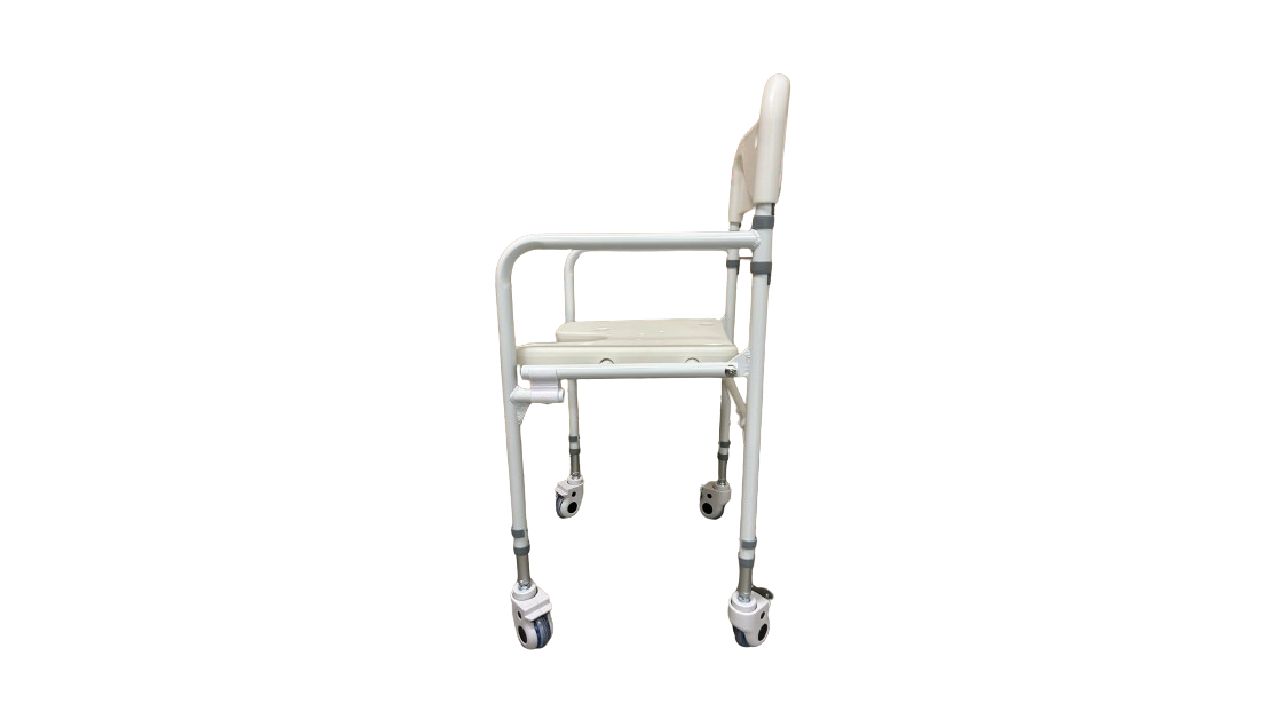 Sedia doccia pieghevole con ruote. Vista laterale. Sedile e schienale beige, telaio bianco, braccioli. Quattro ruote.