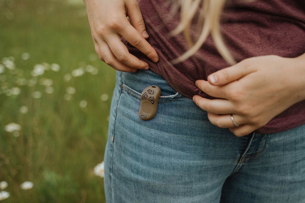 Persona con Tickless Eco Erwachsene nella tasca dei pantaloni. Marrone, con linguetta rossa.