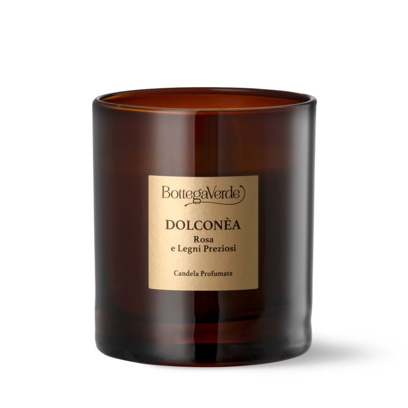 Candela profumata in vetro marrone. Etichetta con "Bottega Verde", "DOLCONÈA", "Rosa e Legni Preziosi" e "Candela Profumata".