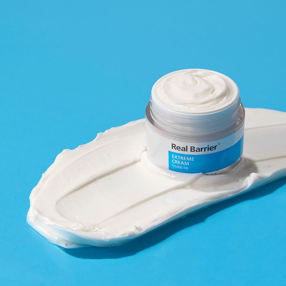 Vasetto di crema aperto su una macchia di crema bianca. Colori blu e bianco. Scritta: Real Barrier, Extreme Cream.