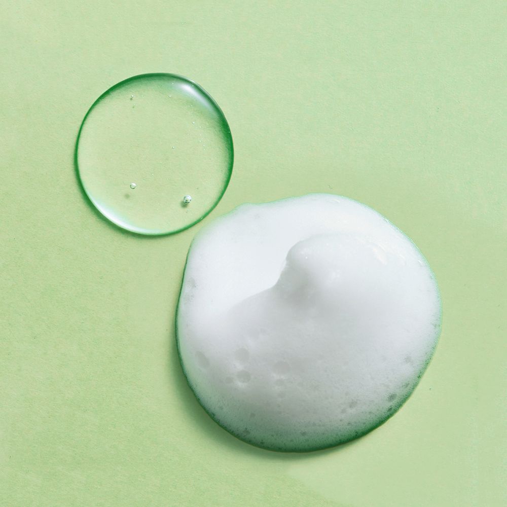 Due cerchi su sfondo verde. Sopra: liquido trasparente. Sotto: schiuma. Nessuna denominazione del prodotto.