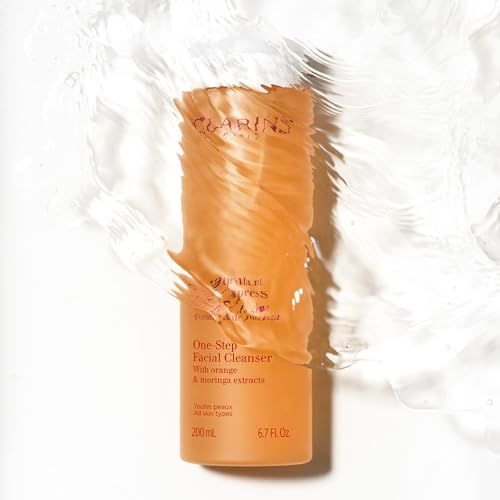 Flacone arancione sott'acqua. Scritte: Clarins Paris, D
emaquillant Tonic Express, One-Step Facial Cleanser.