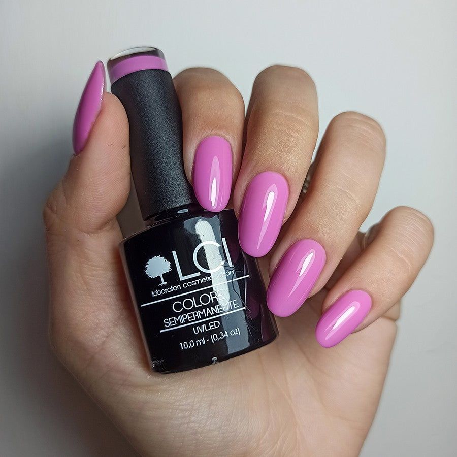 Mano con unghie smaltate e flacone di smalto. Colore rosa. Scritta: LCI, Colore Semipermanente, UVLED.