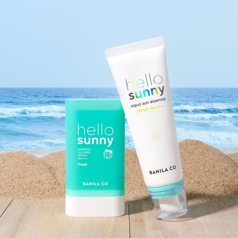 Due prodotti solari Banila Co. Hello Sunny: un tubetto di essenza solare e uno stick solare su sfondo di spiaggia.