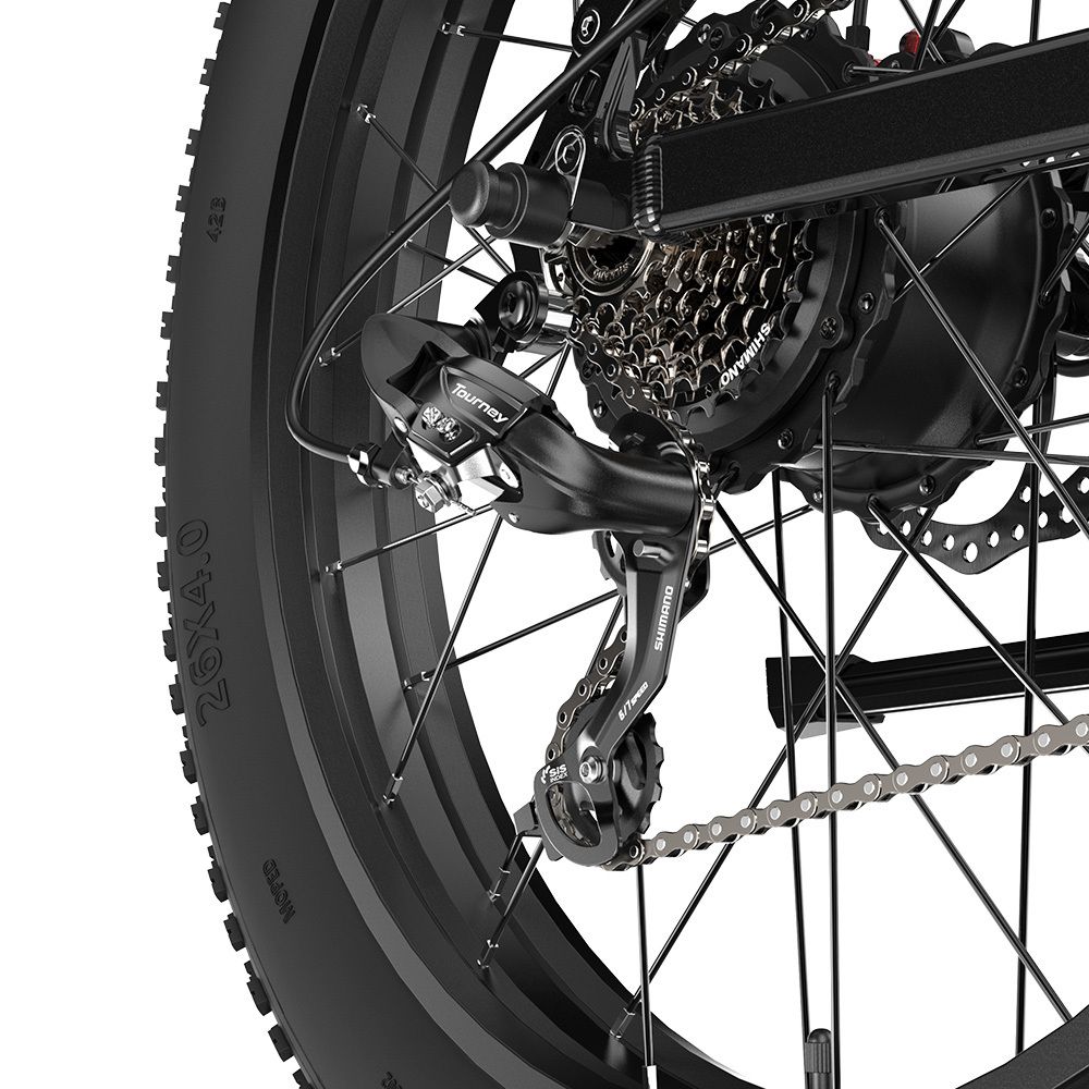 Dettaglio del cambio di una bici nera. Catena e pneumatico. Scritta Tourney.